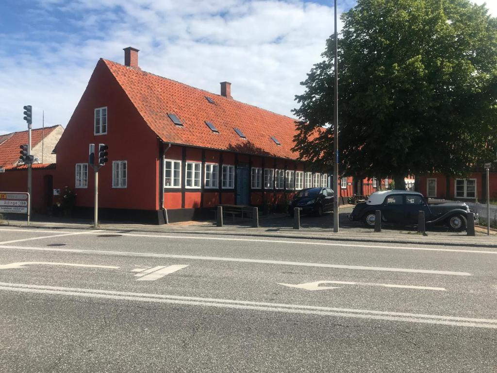 ein rotes Gebäude mit einem davor geparkt in der Unterkunft Toldboden Anno 1684 in Rønne