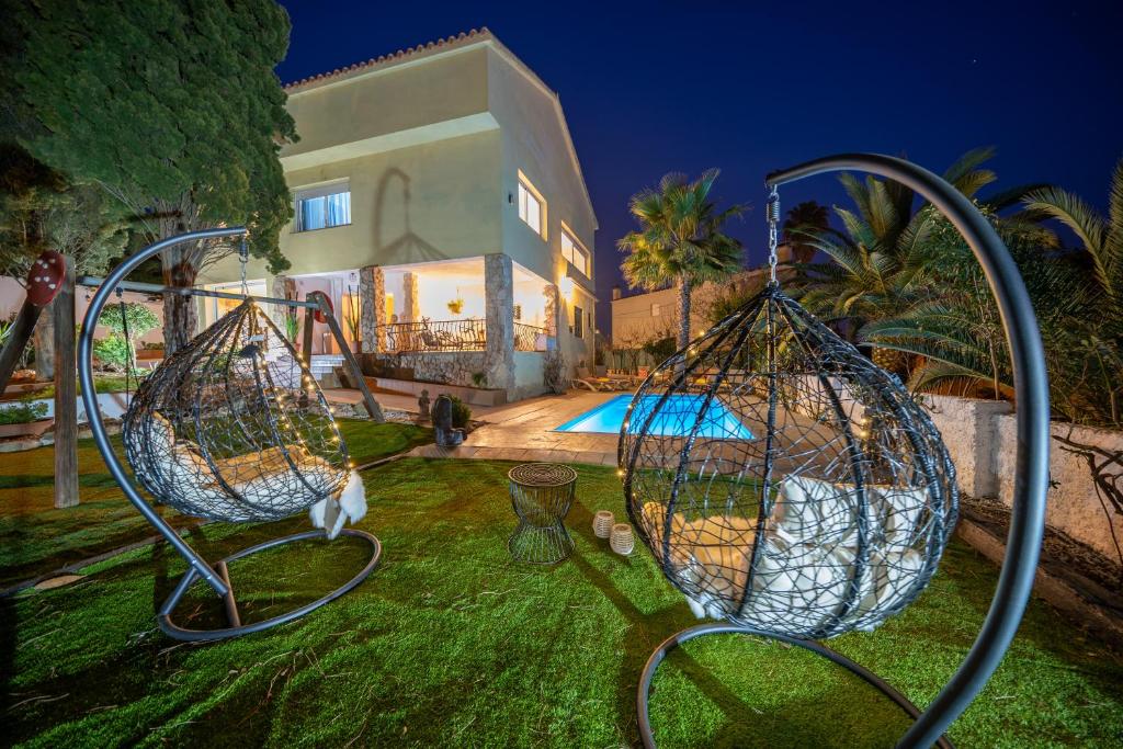 a yard with two swings in front of a house at VIlla Lux Gallery, Ideal Familias o Grupos con Piscina & Aircon in Lloret de Mar