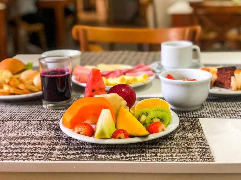 um prato de frutas numa mesa com outros pratos de alimentos em Hotel Di Sica em Balneário Camboriú