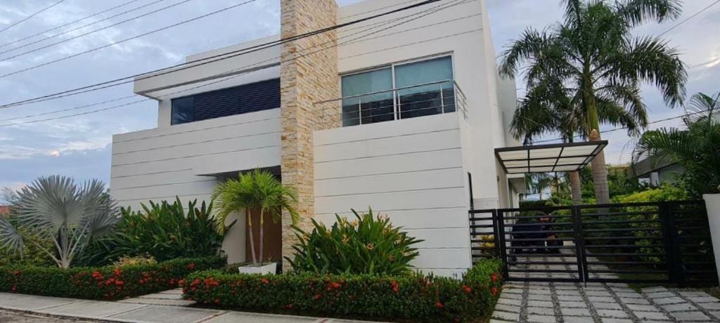 una casa blanca con palmeras delante en Casa Campestre en Condominio Lagos Del Peñon, en Girardot