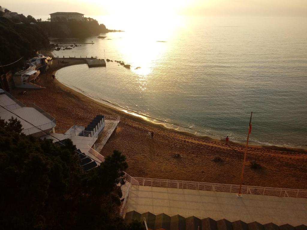 a beach with the sun shining on the water at Caletta Beach in Castiglioncello