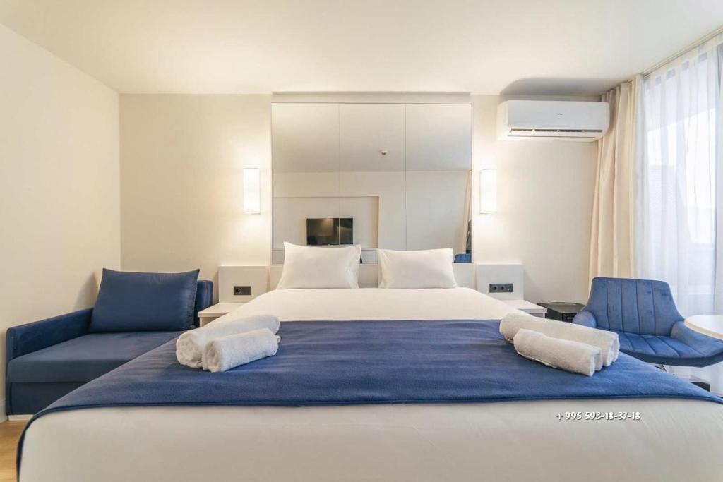 a bedroom with a large bed and two blue chairs at ORBI City studio 536 in Batumi
