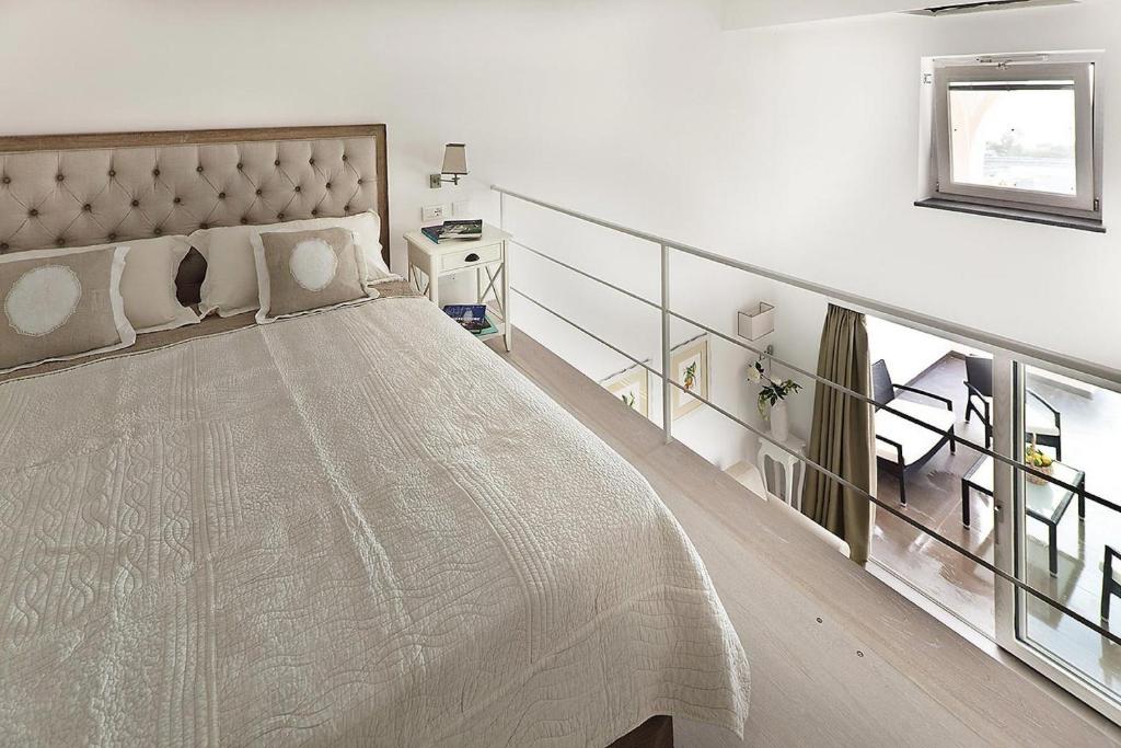 a white bedroom with a large bed and a staircase at Tenuta Del Poggio Antico in Ischia