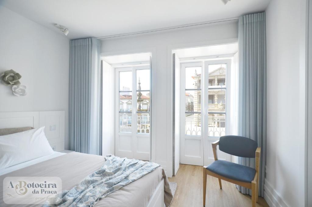 - une chambre avec un lit, une chaise et des fenêtres dans l'établissement A Botoeira da Praça guest house, à Viana do Castelo