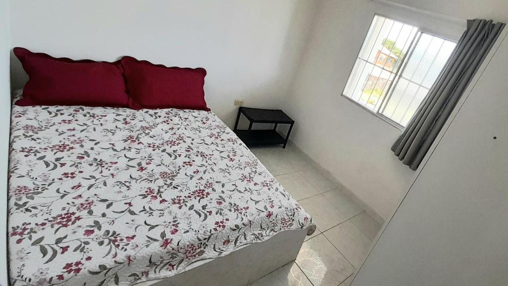 a bedroom with a bed with a red pillow and a window at Ap06-A 50 Metros da Praia Flats Mobiliados para 4 Pessoas in Paulista
