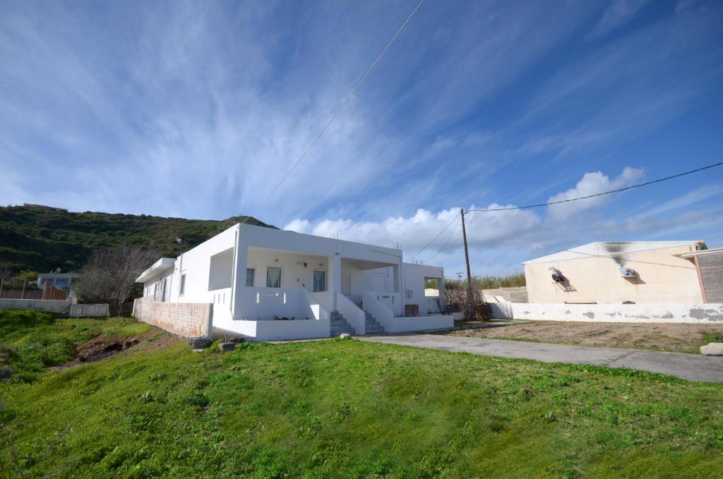 een wit huis op een grasveld met een heuvel bij Studio Anthoula in Kefalos