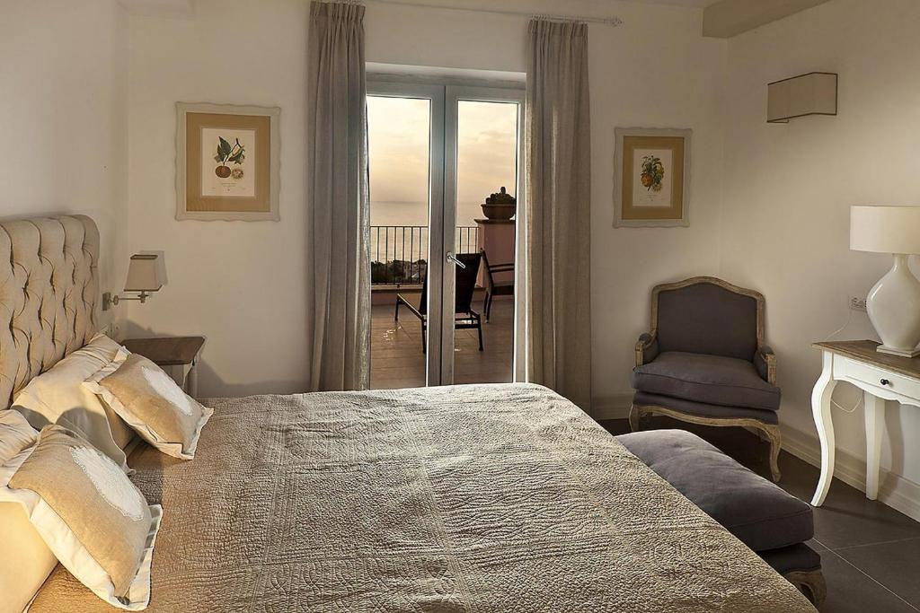 a bedroom with a bed and a chair and a balcony at Tenuta Del Poggio Antico in Ischia