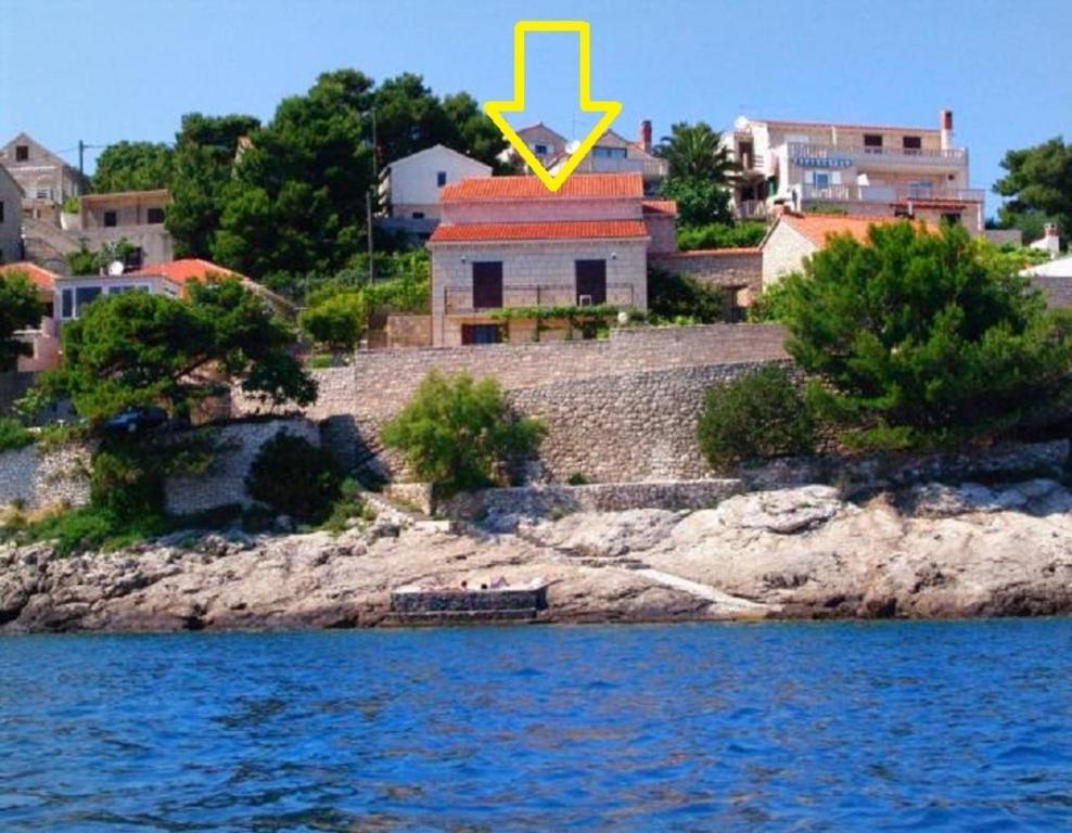 un bâtiment avec une flèche jaune au-dessus dans l'établissement Apartments and rooms Ref - 20 m from sea, à Sumartin