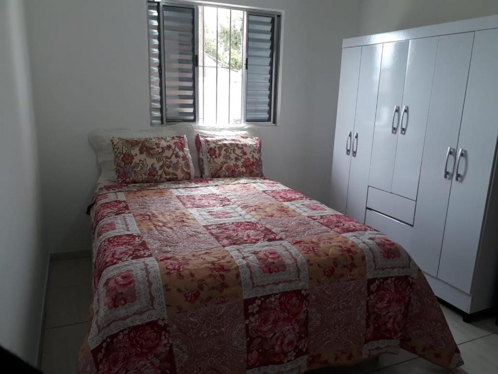 ein Schlafzimmer mit einem Bett mit einer roten Decke und einem Fenster in der Unterkunft Cantinho do Nono in Campos do Jordão