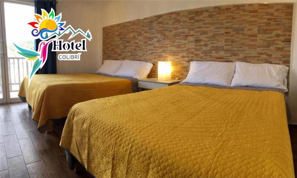 une chambre d'hôtel avec 2 lits et un panneau mural dans l'établissement HOTEL COLIBRÍ, à Creel