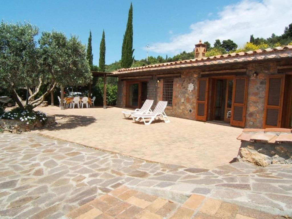 a patio with two lounge chairs and a house at Villa Raggio Di Sole in Porto Santo Stefano