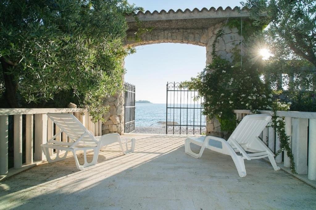 zwei weiße Stühle auf einer Veranda mit Meerblick in der Unterkunft Holiday home Villa More - 10m from sea in Rogoznica