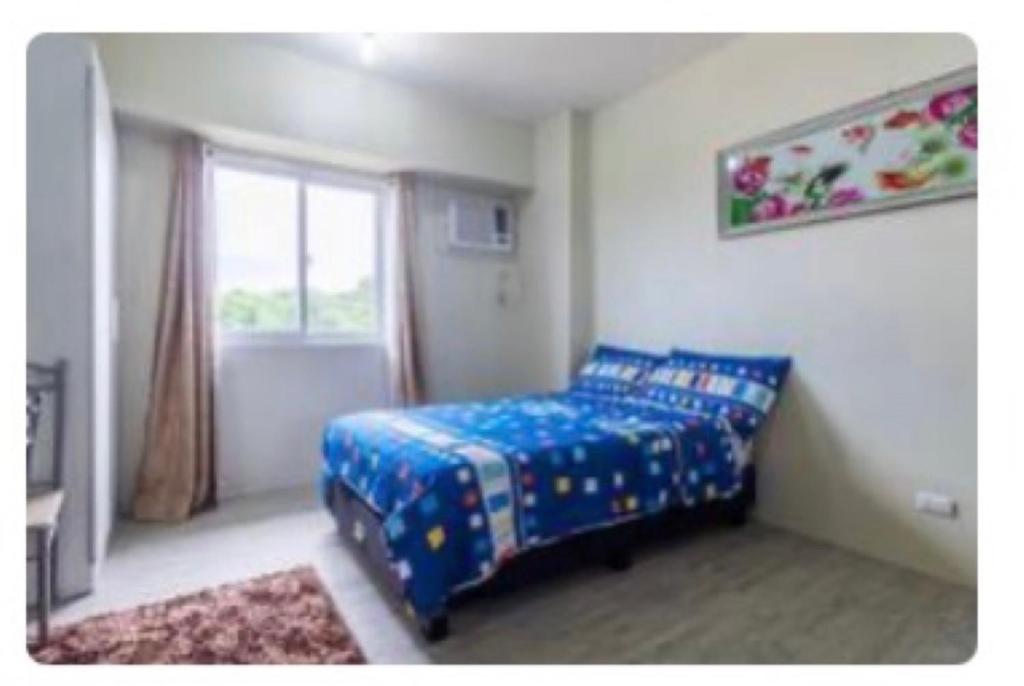 a bedroom with a blue bed and a window at Staycation condo with pool near SM Tungko, Bulacan in Mangangpico