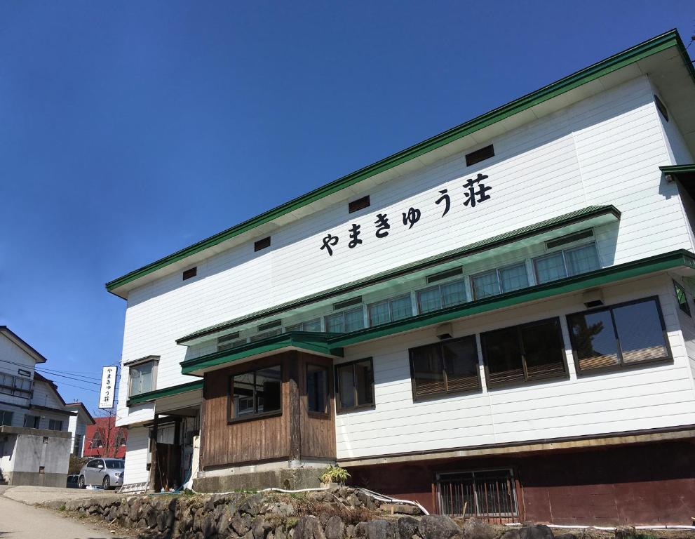 a building with asian writing on the side of it at Yamakyuso in Otari