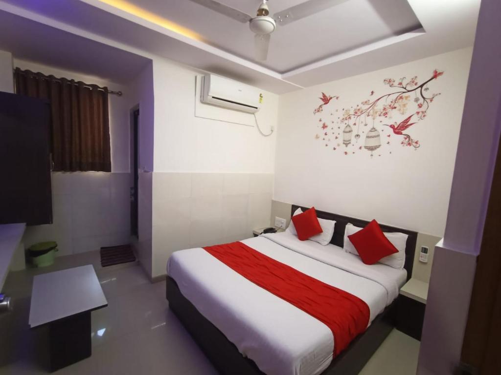Hotel Gopi Palace في أحمد آباد: غرفة فندق بسرير ومخدات حمراء