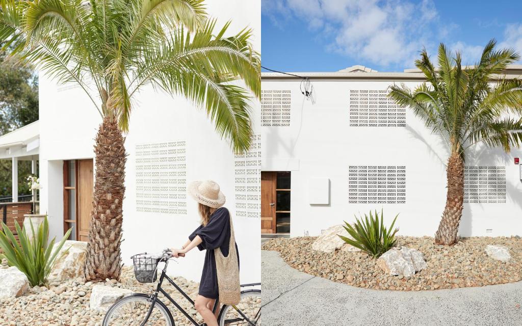 a woman walking a bike next to a palm tree at The Brunswick, Brunswick Heads in Brunswick Heads