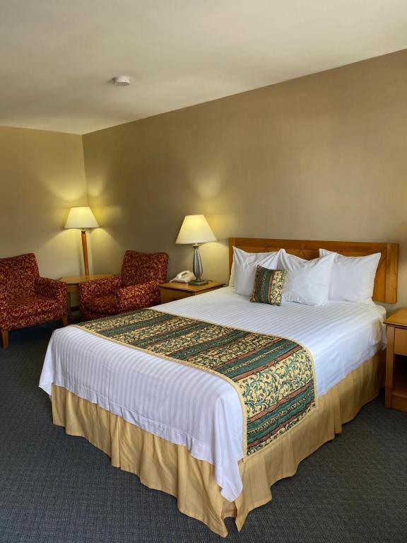 a hotel room with a large bed and two chairs at Thunderbird Motor Lodge, Norman, OK in Norman