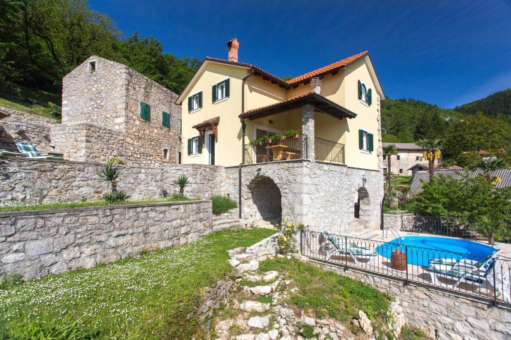 una gran casa de piedra con una piscina frente a ella en Villa Sirotnjak, en Lovran