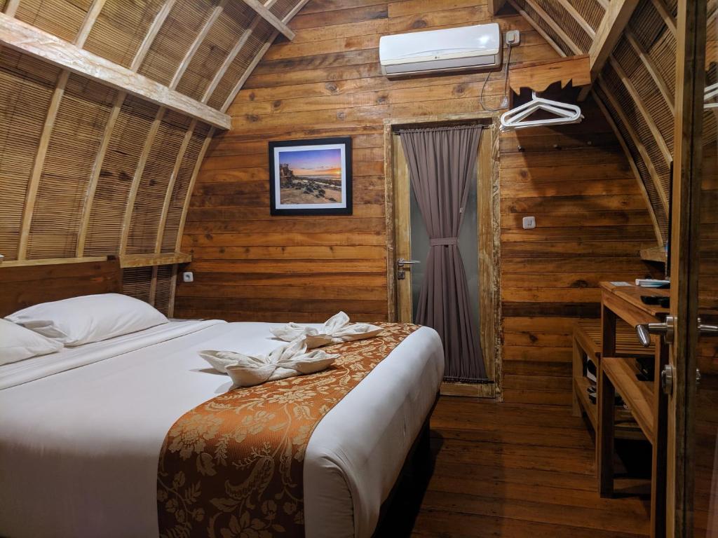 a bedroom with a bed in a room with wooden walls at Paradesa Villa in Gili Trawangan