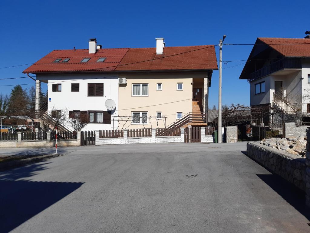 una gran casa blanca con techo rojo en una calle en Apartman Helena, en Slunj