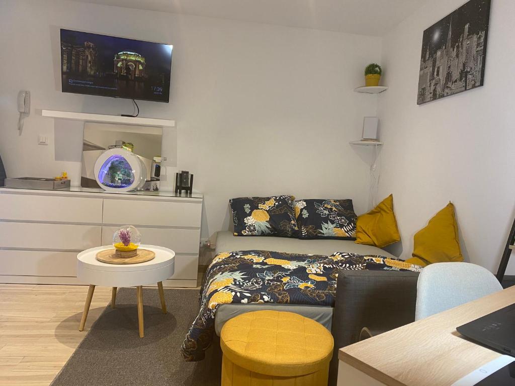 una pequeña sala de estar con cama y mesa. en Le studio à découvrir., en Marquette-lès-Lille