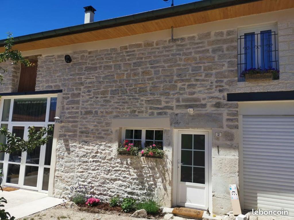 une maison en pierre avec des fleurs dans une fenêtre dans l'établissement Charmant appartement dans maison de village, à Mesnois