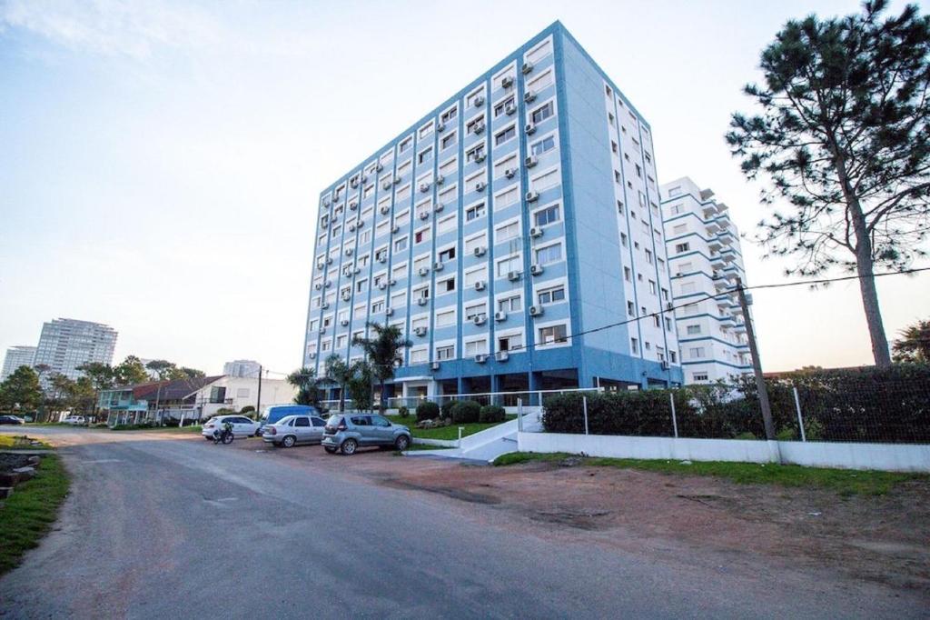 duży niebieski budynek z samochodami zaparkowanymi przed nim w obiekcie Apartamento de un dormitorio en Edificio "Luna de Mar" w mieście Punta del Este