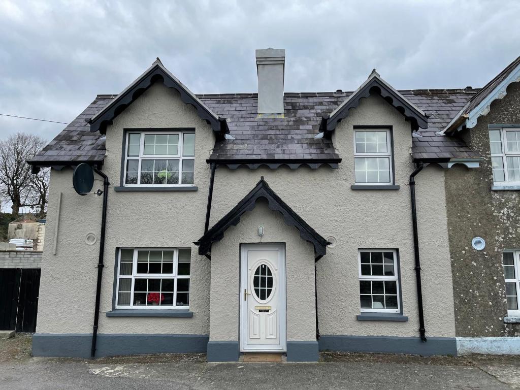 une maison avec une porte et des fenêtres blanches dans l'établissement Creamery Cottage, à Kenmare