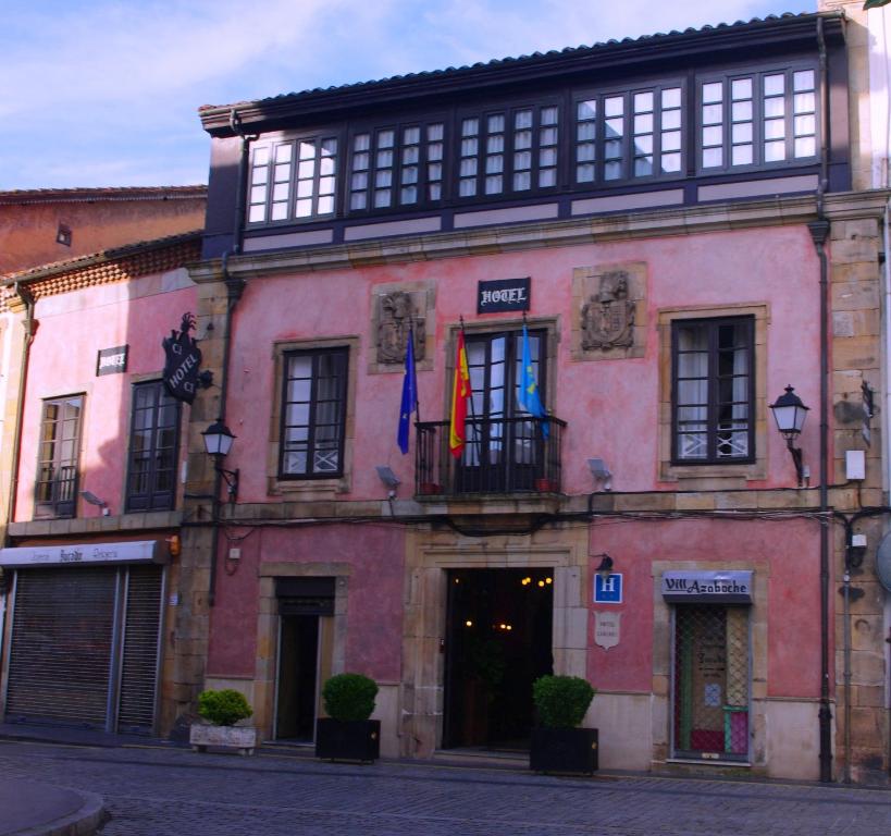 um edifício rosa com bandeiras na frente em Hotel Palacio Carlos I em Villaviciosa