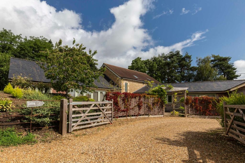 uma casa com um portão de madeira e uma cerca em Clubhouse Cottage em Lacock