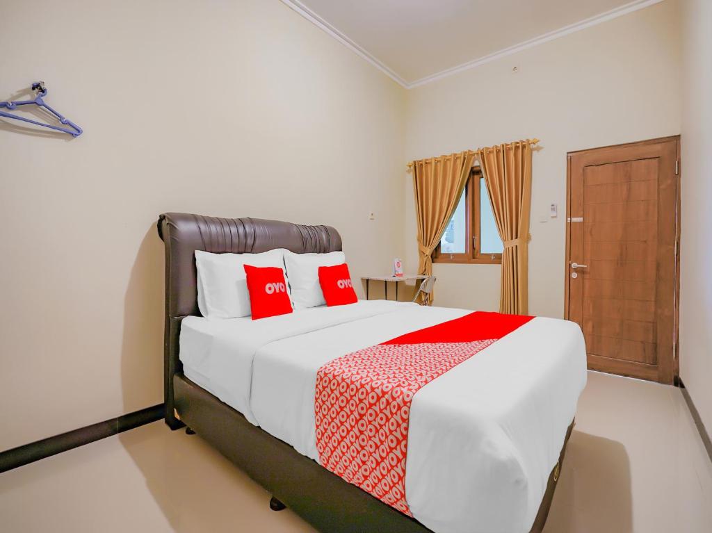 a bedroom with a large bed with red pillows at Super OYO 90210 Kenari House Syariah in Yogyakarta