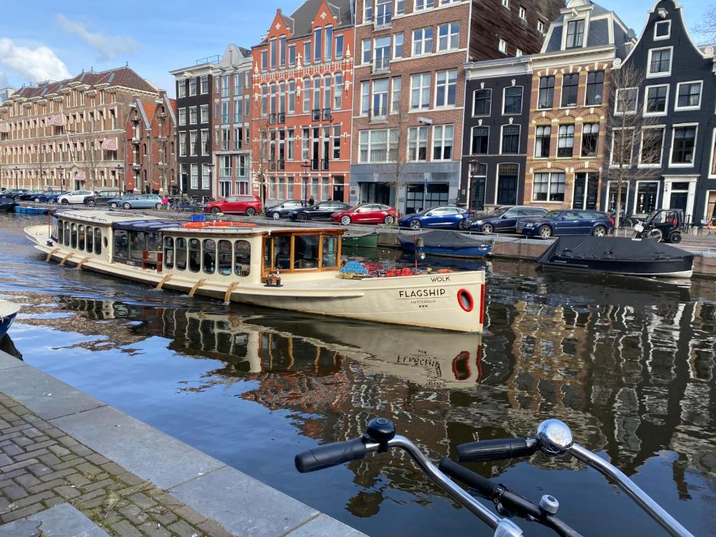 un barco en un canal en una ciudad con edificios en Prinsengracht Museum Bed and Breakfast, en Ámsterdam