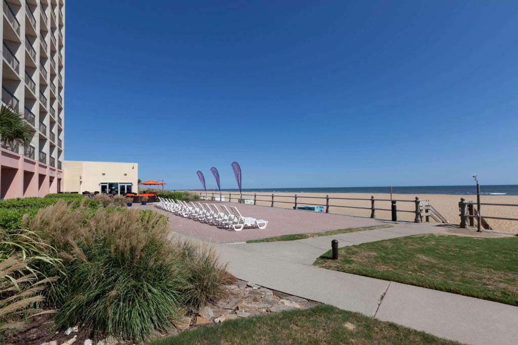 a beach with lounge chairs and a building and the ocean at Wyndham Virginia Beach Oceanfront in Virginia Beach