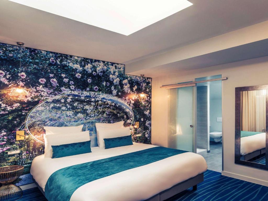 um quarto com uma cama grande e uma parede floral em Hôtel Mercure Paris Suresnes Longchamp em Suresnes