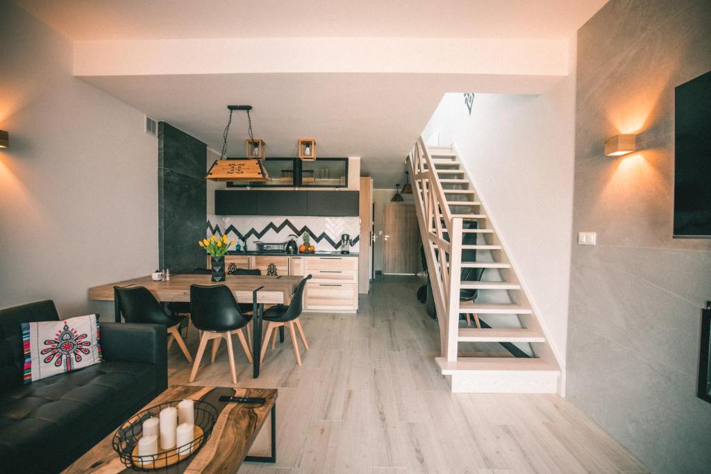 a living room with a staircase and a table and chairs at RelaxApart - Komfortowy apartament Pod Stokiem in Szczyrk