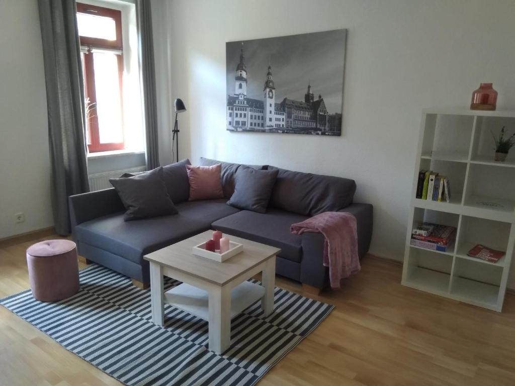 ein Wohnzimmer mit einem blauen Sofa und einem Tisch in der Unterkunft Ferienwohnung Rudi in Chemnitz
