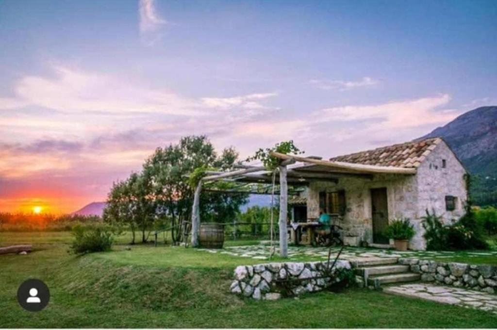 ein kleines Haus auf einem Feld mit Sonnenuntergang im Hintergrund in der Unterkunft Vineyard Eco Cottage near Dubrovnik in Gruda