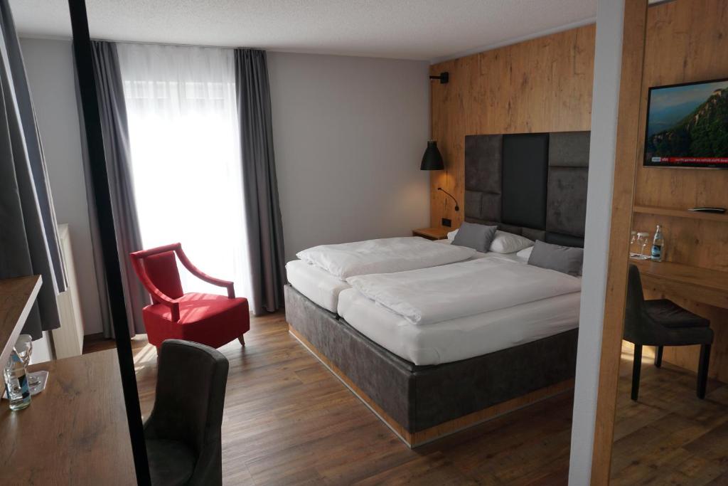 a hotel room with a bed and a red chair at Hotel Grüner Baum in Kaufbeuren