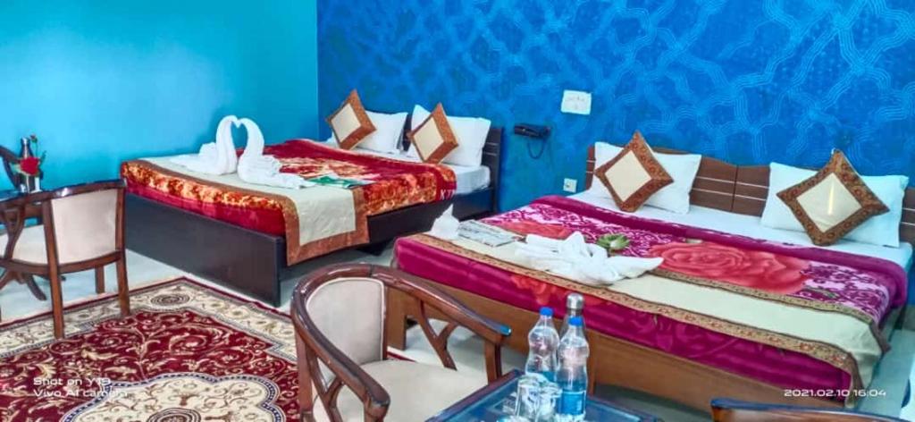 a room with two beds and a table and chairs at Hotel Anand LOK in Rājgīr