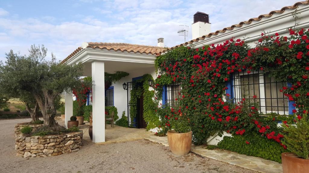 una casa con flores rojas a un lado. en Finca El Romeral, en Alpera