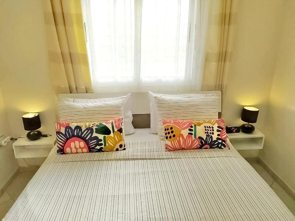 ein Bett mit vier Kissen und einem Fenster in der Unterkunft Reta-Inn Martil Beach in Martil