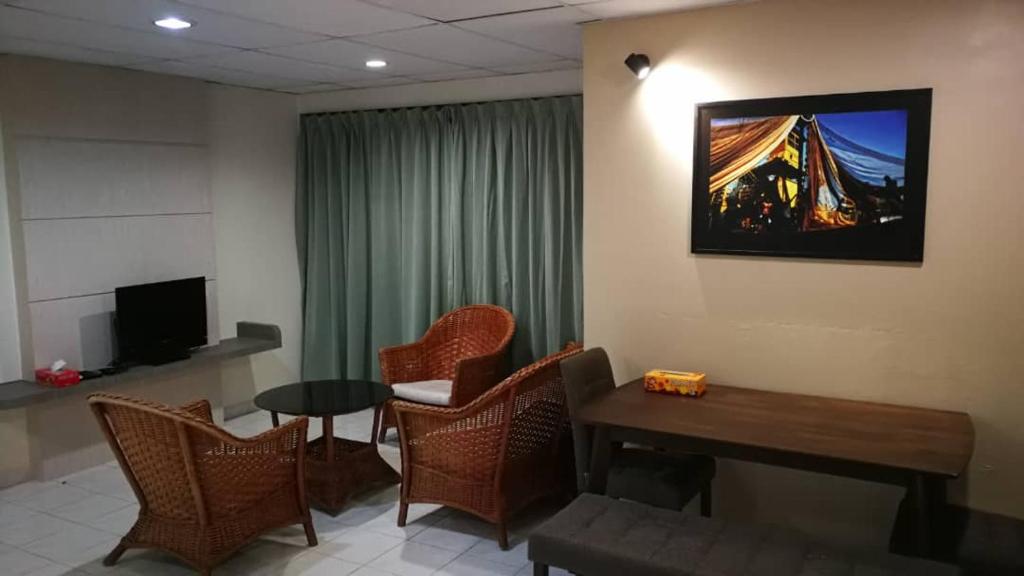 Pangkor staycation apartment في بانكور: غرفة معيشة مع طاولة وكراسي وتلفزيون