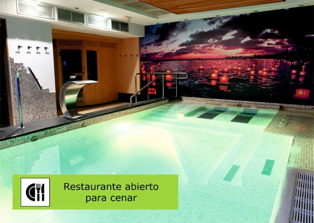 a swimming pool in a building with a painting on the wall at Hotel Spa QH Centro León in León