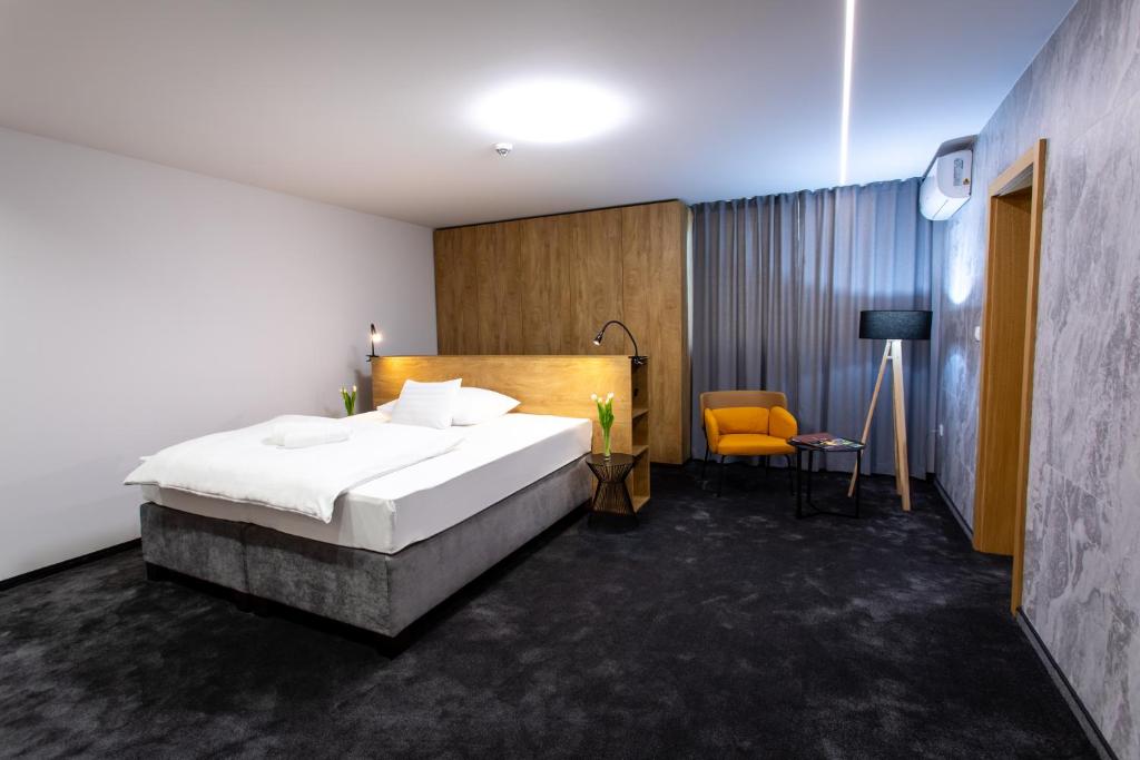 Hotel Novy Kastiel - Self check-in في توبولتشاني: غرفة نوم بسرير كبير وكرسي اصفر