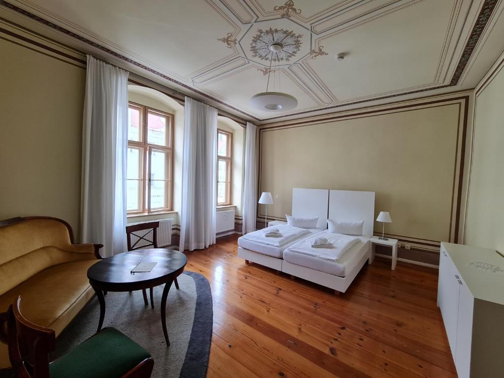 uma sala de estar com duas camas e uma mesa em Hotel Cranach-Herberge City Centre em Wittenberg