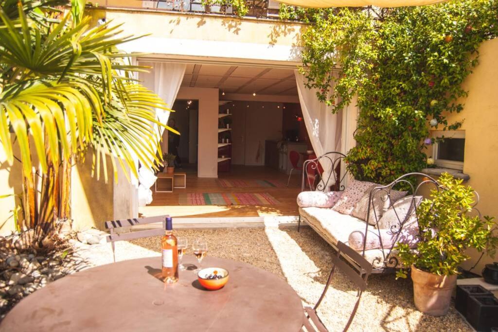 a patio with a table and a couch at Ecrin de verdure avec accès piscine en plein Aix in Aix-en-Provence