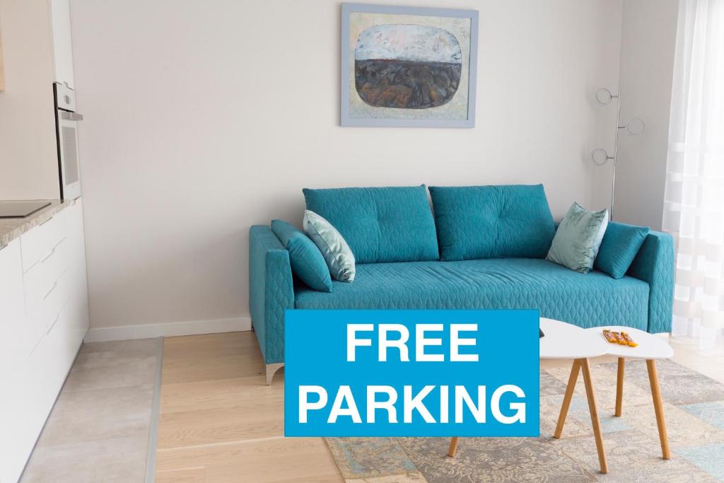un sofá azul en la sala de estar con un cartel de aparcamiento gratuito en Chopin Apartments, en Cracovia