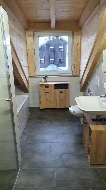 uma casa de banho com um lavatório, um WC e uma janela. em Ferienapartment bavarian living em Moosinning