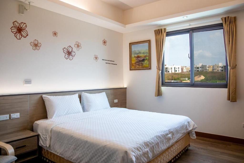 馬公市的住宿－沐夏風情民宿，一间卧室设有一张大床和一个窗户。