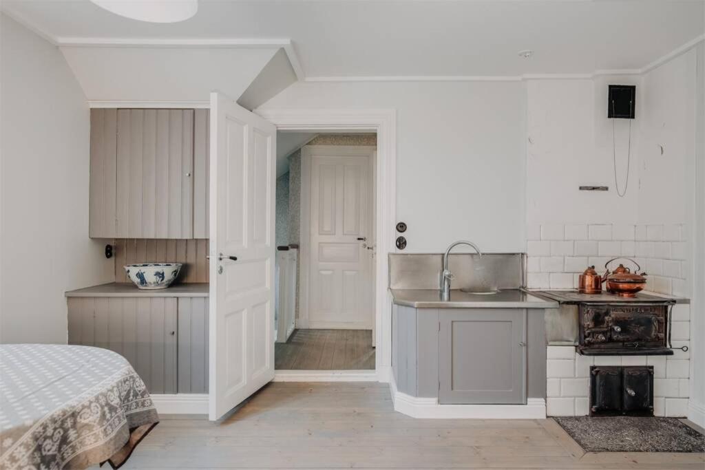 a kitchen with white cabinets and a sink and a bed at Casa Fontenay charmig lägenhet nära stadsparken och Vättern in Hjo